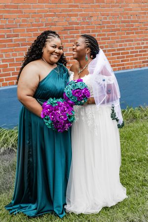 Wedding couple in teal and white dresses share joyful moments during outdoor photo session.