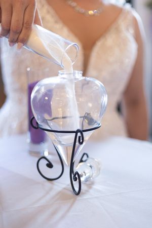 Glass candle holders with black metal stands arranged on a white tablecloth at a wedding reception.