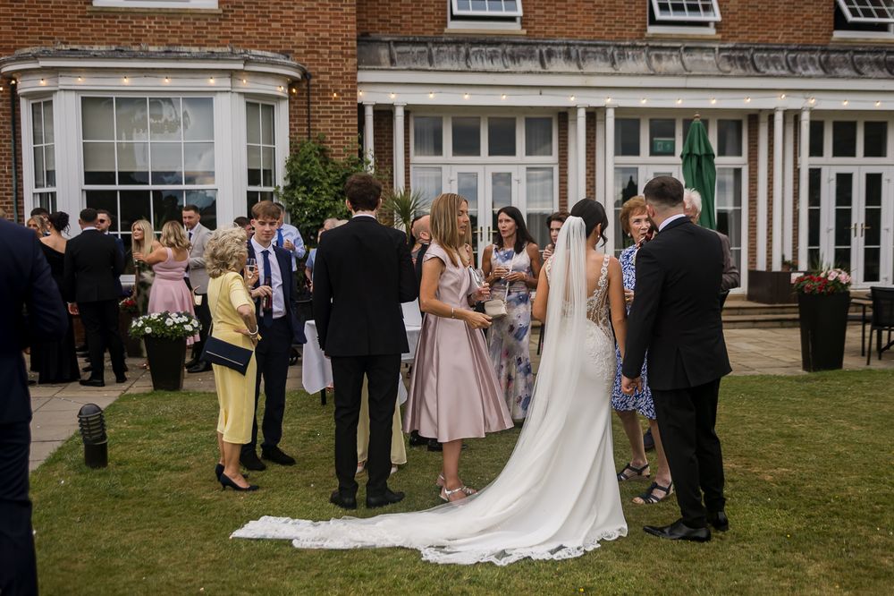 Wedding reception gathering outside historic brick building with guests on lawn.