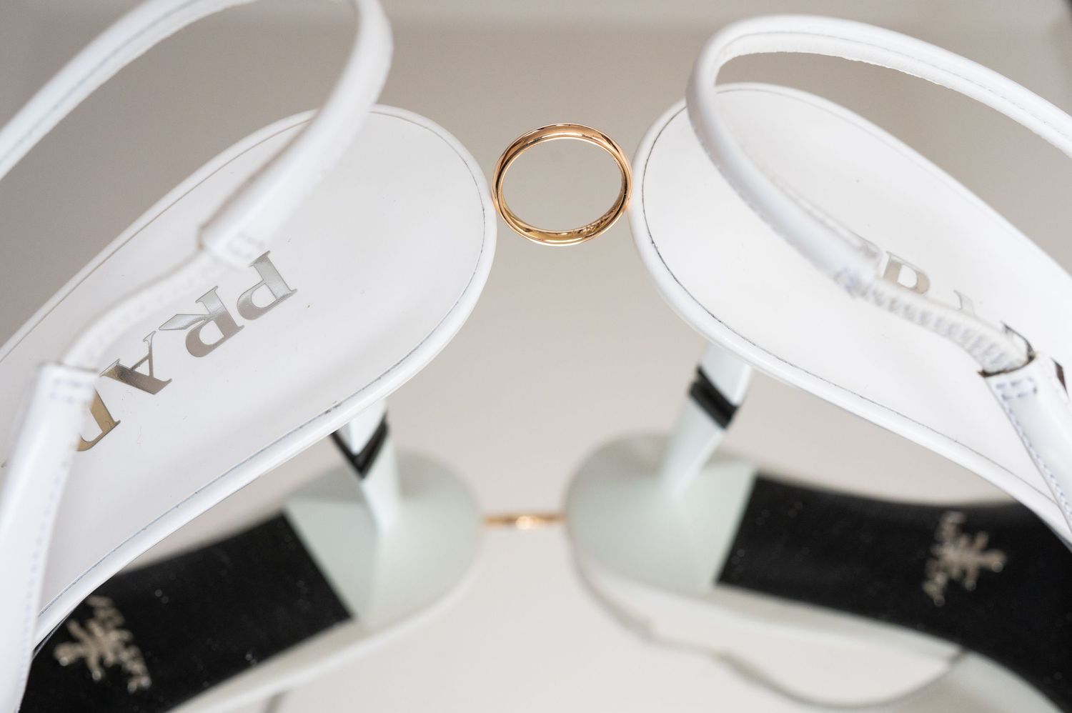Close-up details of white wedding stationery and delicate gold rings.
