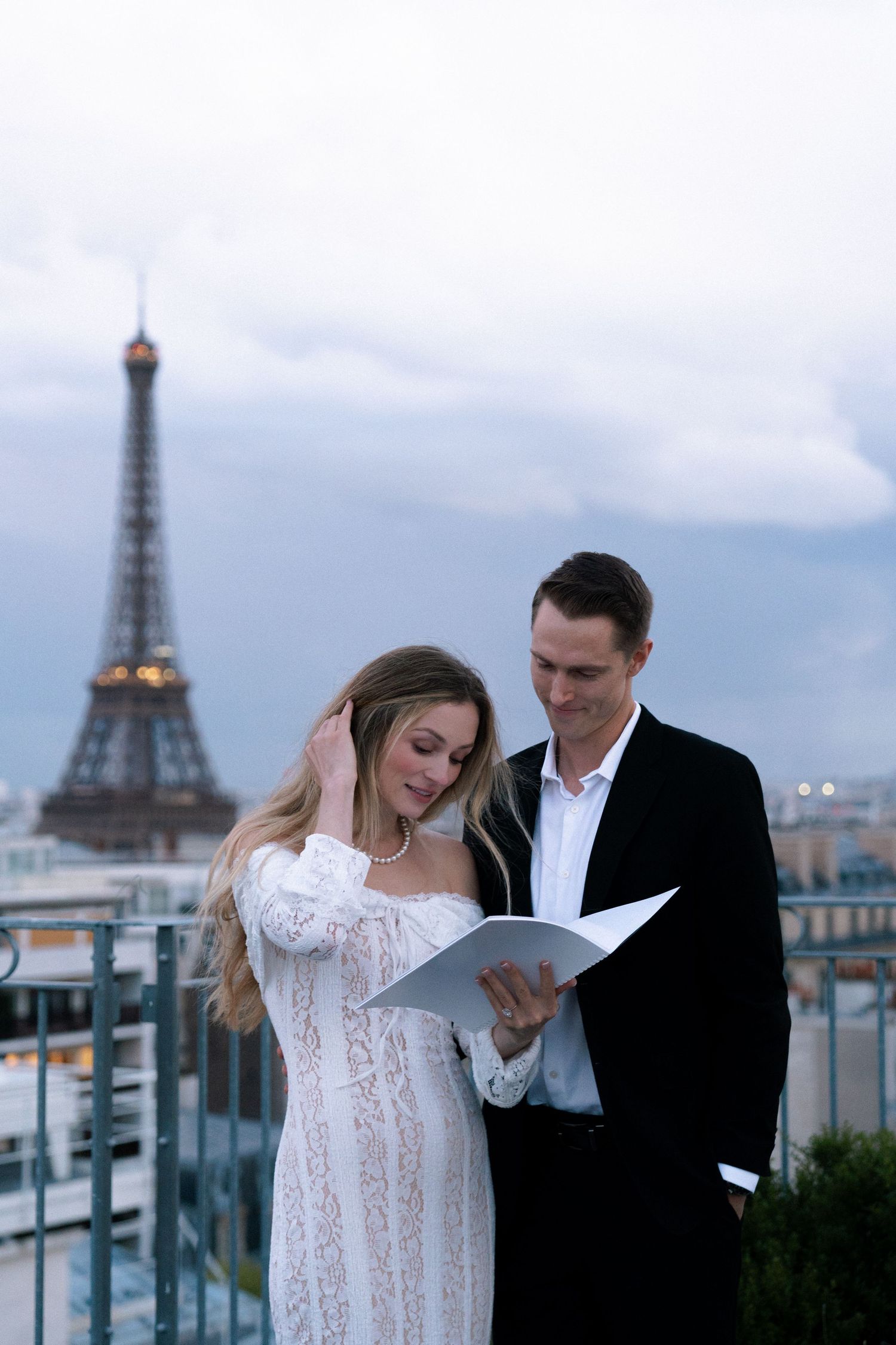 A romantic couple shares an intimate moment on a rooftop terrace with the iconic Eiffel Tower visible in Paris.