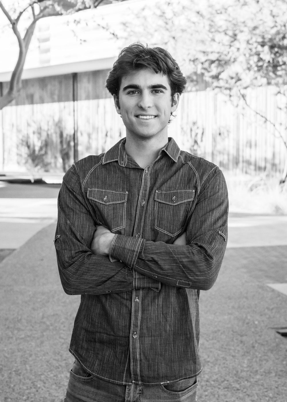 Black and white portrait of man in striped denim shirt with crossed arms.