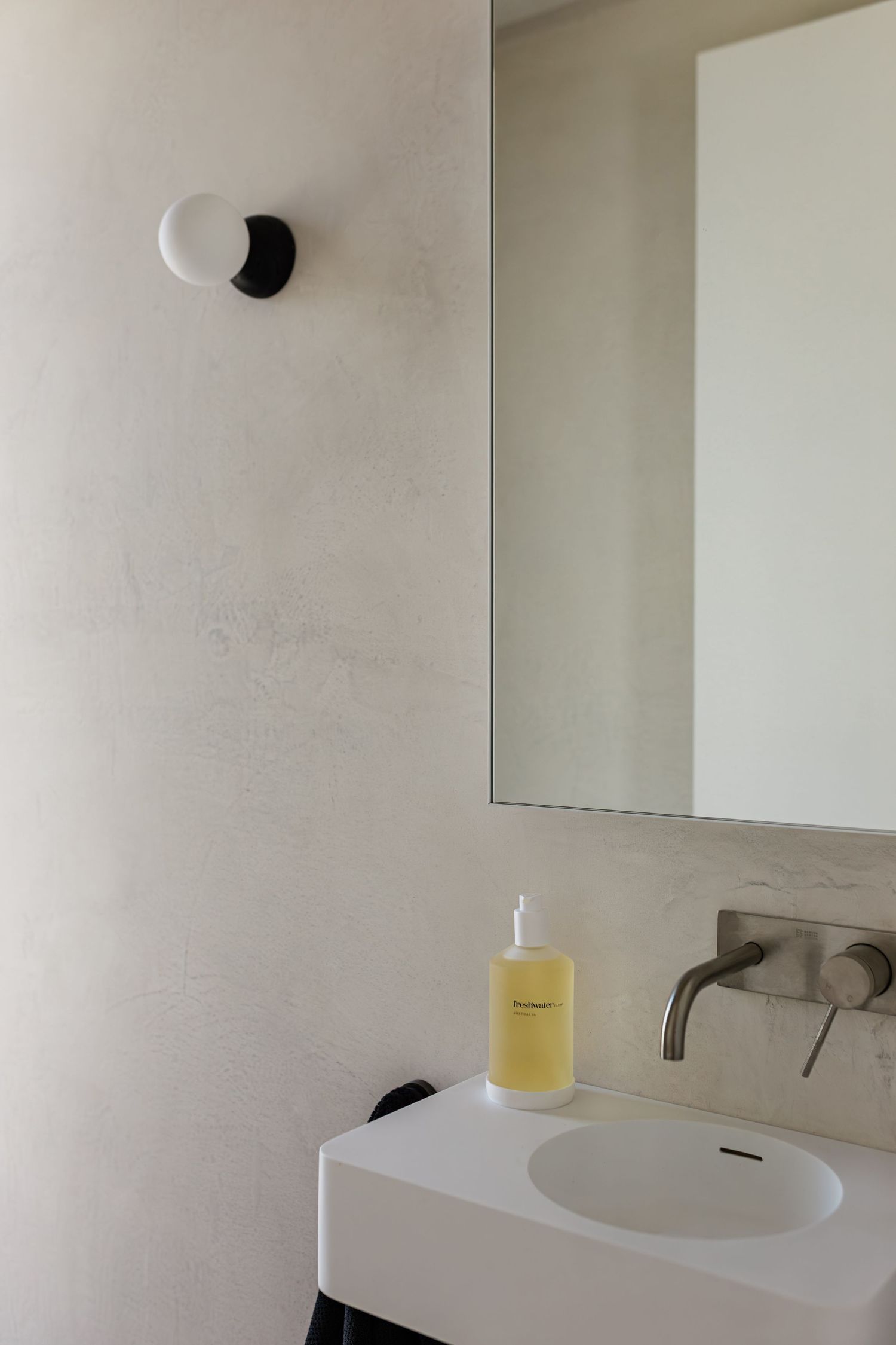 Modern minimalist bathroom interior with white walls, black window frame, and sleek wall-mounted fixtures.
