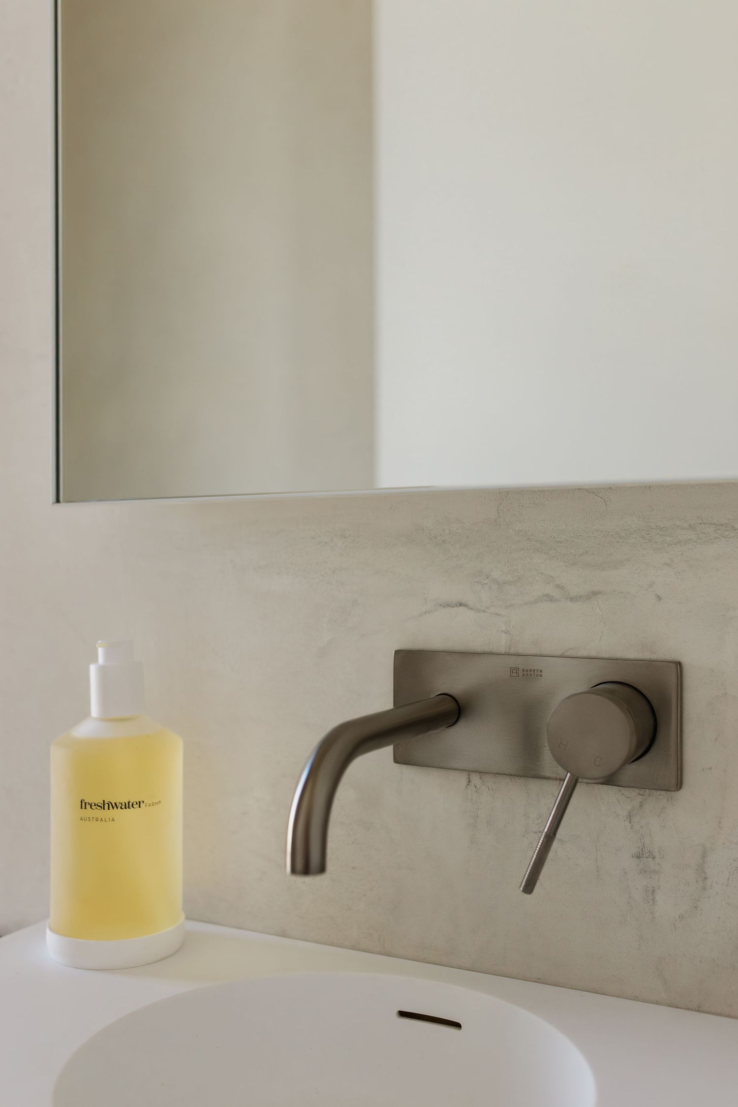 Modern bathroom interior with wall-mounted faucet and sleek minimalist design features against light beige walls.