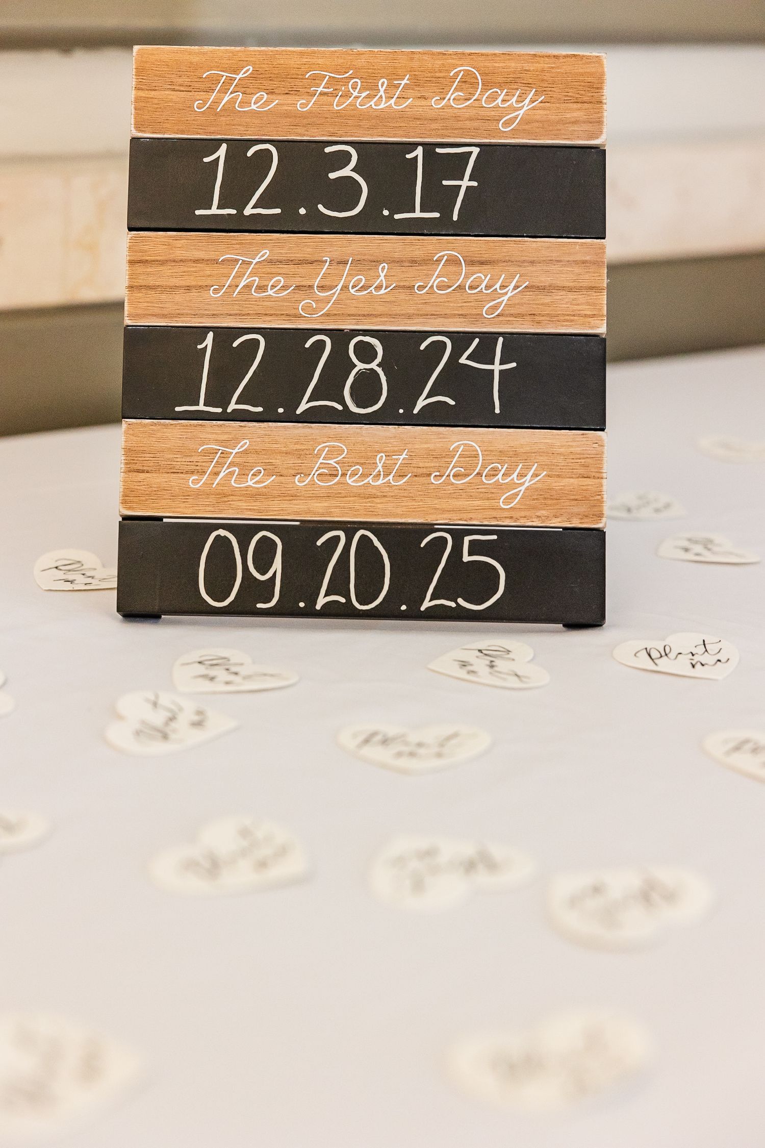 Wooden blocks with handwritten dates and phrases 'The First Day' and 'The Best Day' displayed on rustic surfaces.