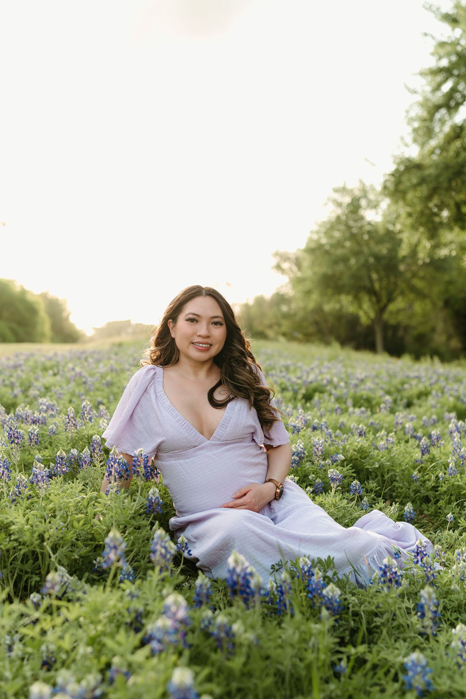 Woman in white dress lying gracefully among blooming bluebonnets in a spring meadow.