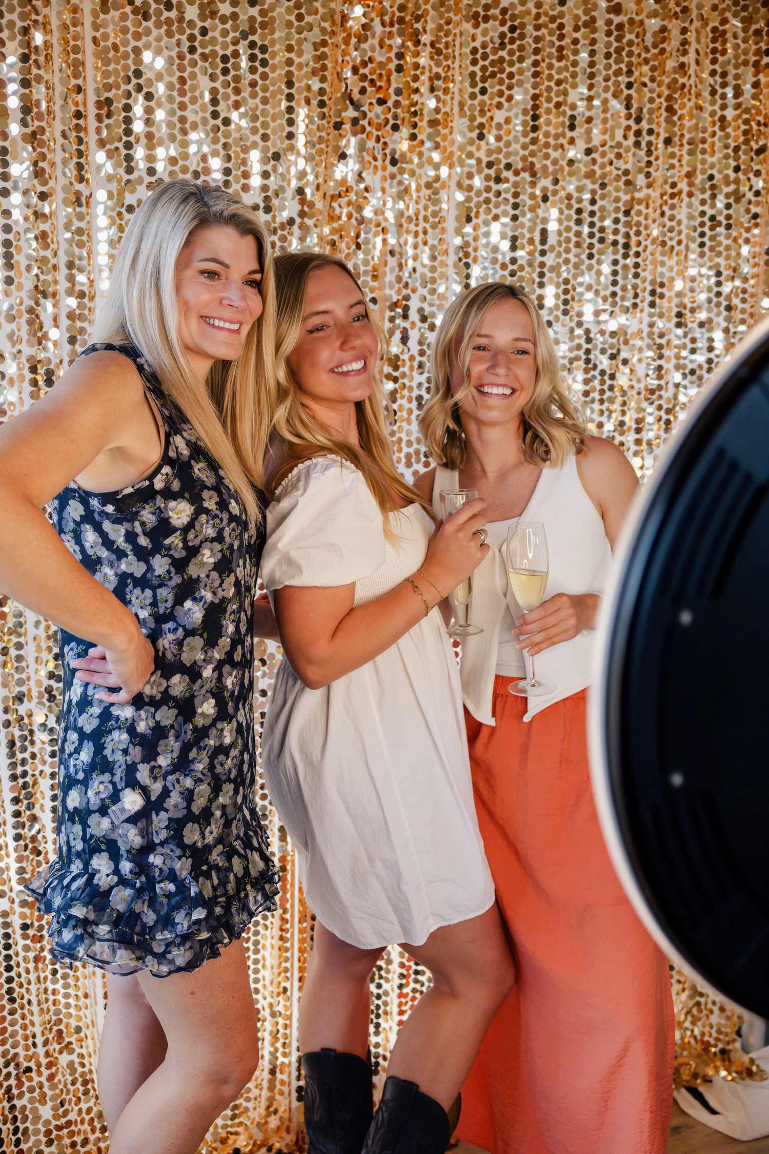 Three partygoers pose together with colorful props and festive attire in a photo booth setting.
