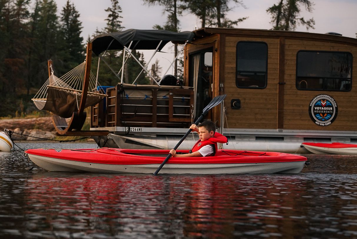 Red kayaks float beside rustic wooden cabin on lakefront.