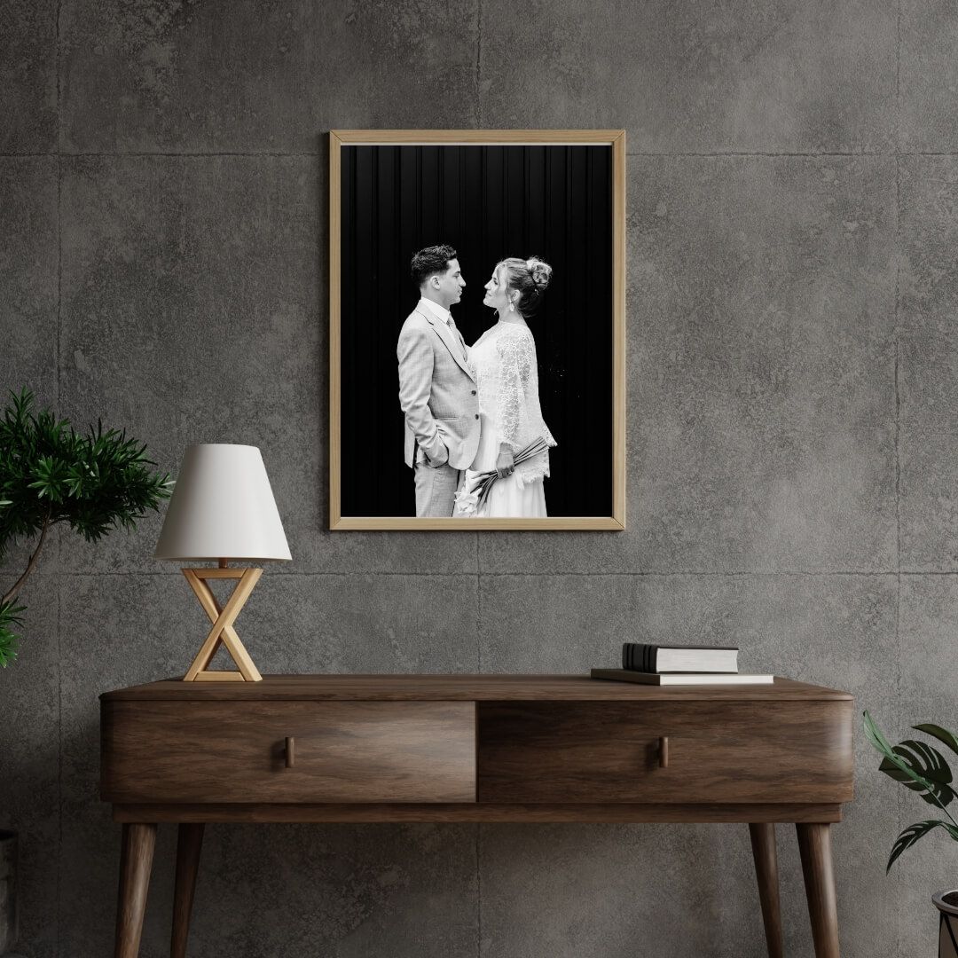 Framed black and white wedding photo displayed on modern console table with lamp.