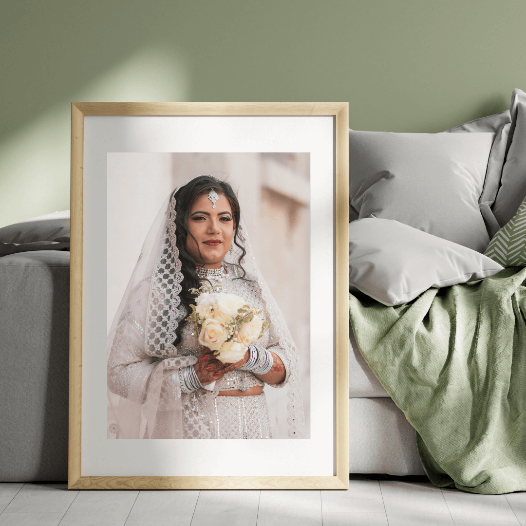 A framed bridal portrait with soft lighting displayed against a green and gray living room wall.