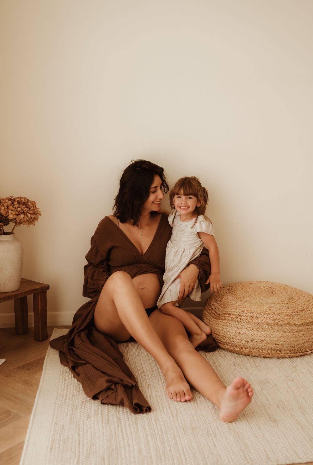 Five warm-toned lifestyle photos showing intimate family moments on a cream carpet with woven baskets in the background.