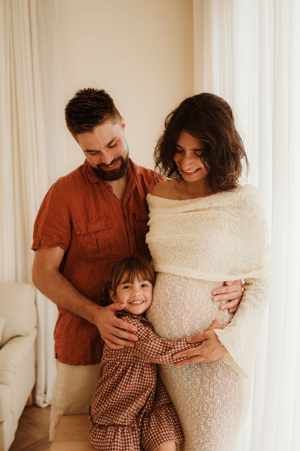 A series of four intimate photos showing a family embracing and sharing joyful moments against a light curtain backdrop.