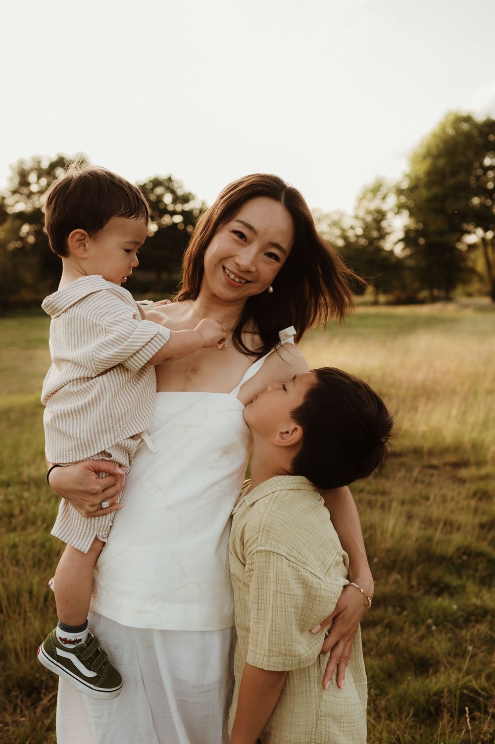 A tender family moment captured at sunset in a grassy field during golden hour.