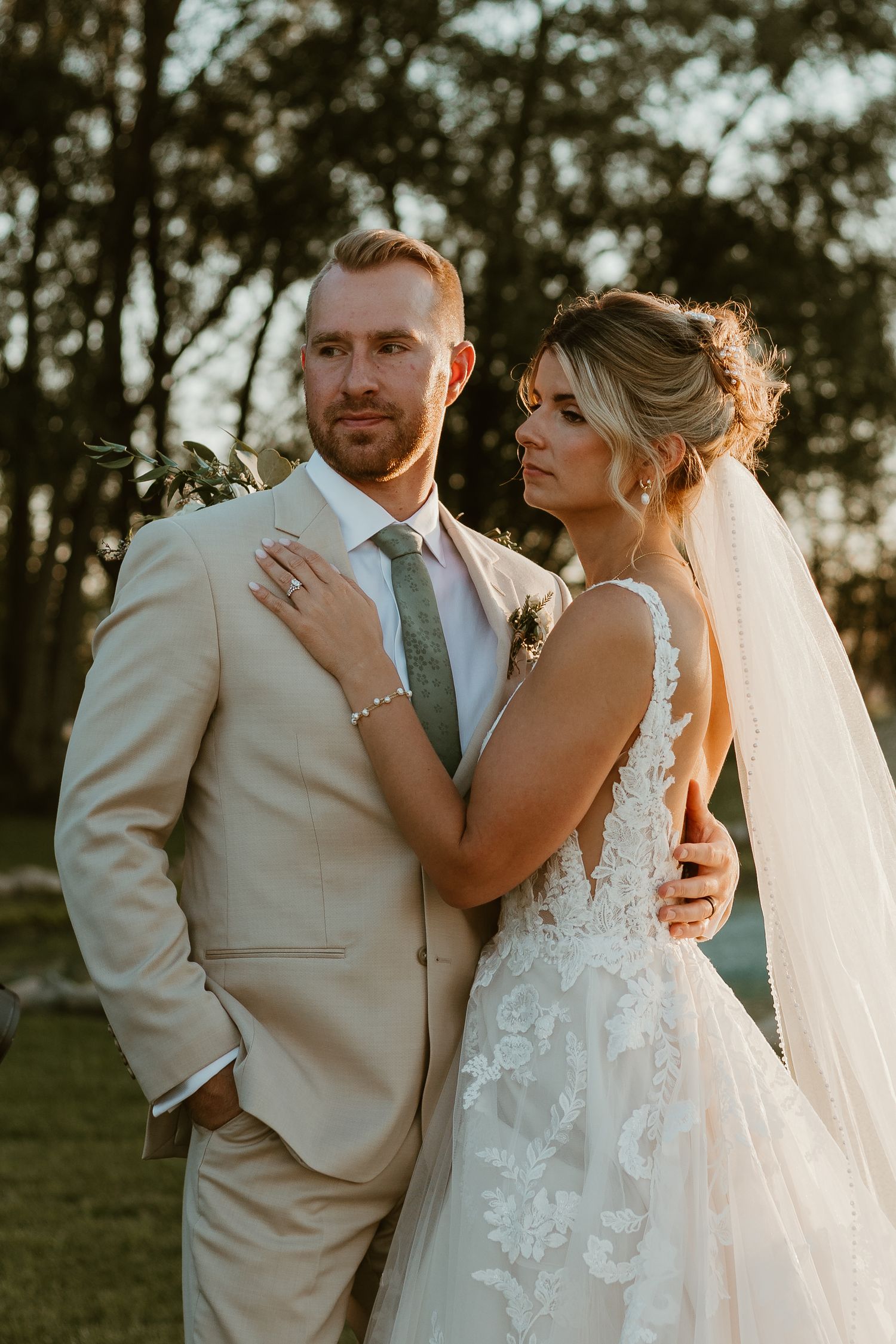 A romantic wedding moment in a forest setting with a lush white floral bouquet and elegant dress and suit.