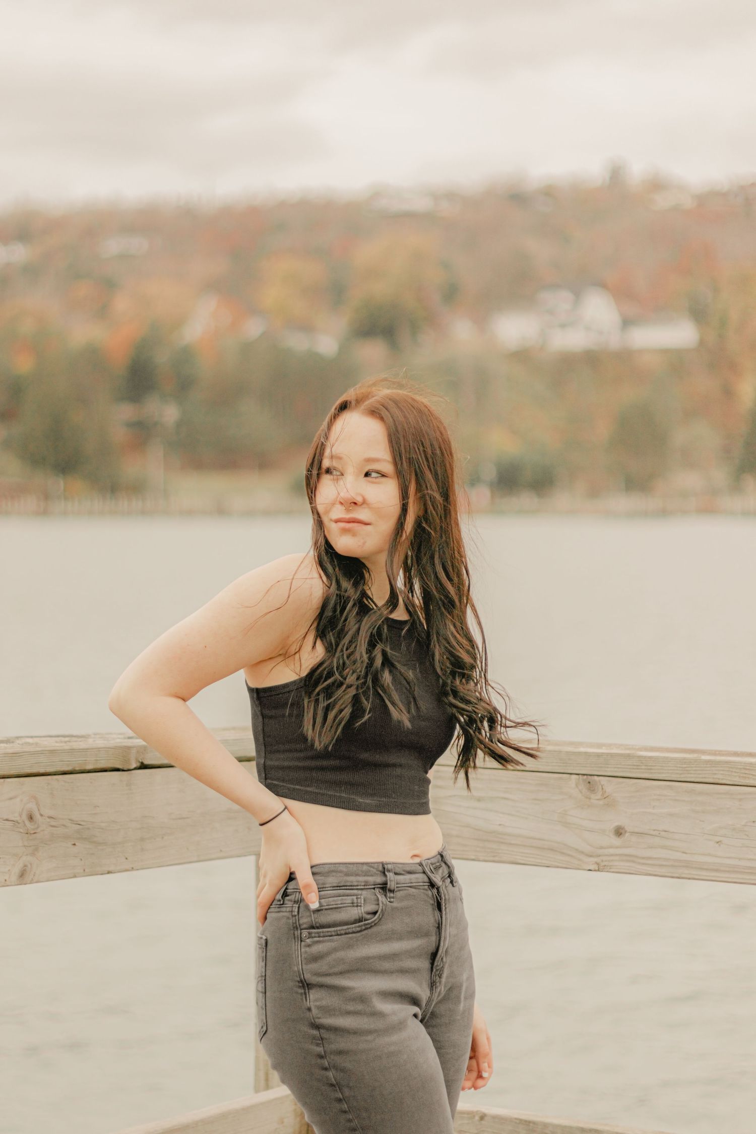 A casual outdoor portrait against an autumn backdrop wearing a black crop top and gray pants.