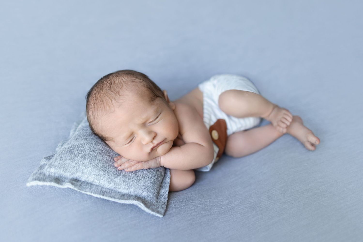 Sleeping baby in white diaper resting on light blue pillow during newborn photoshoot. Photos by Tampa Photographer DigitalMyst Photography