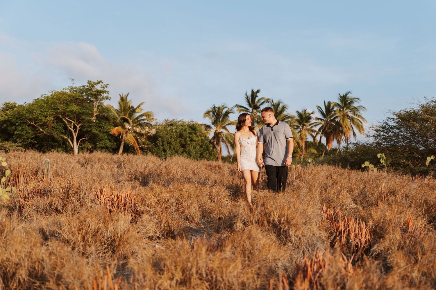 A happy family poses together beneath palm trees on a sunny beach during a tropical vacation.