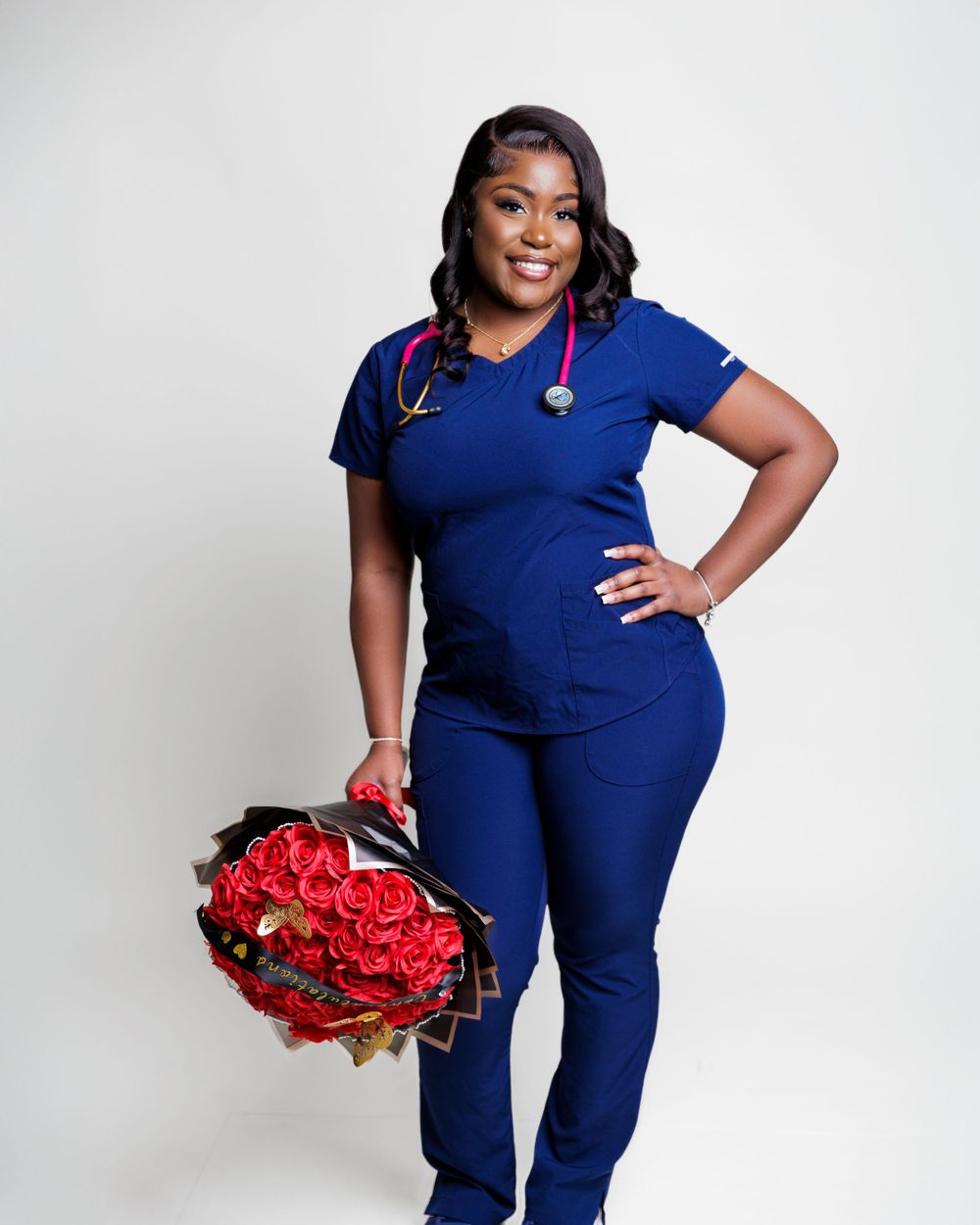 A medical professional portrait in navy blue scrubs holding a red bouquet.