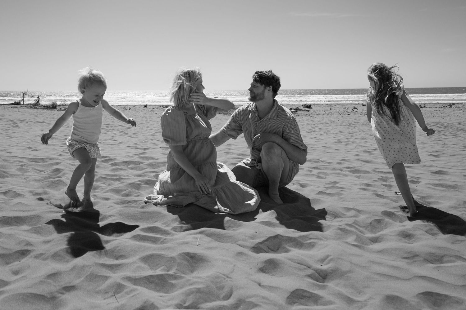 kids running around mum and dad during family/ maternity session at the beach during the day in Christchurch