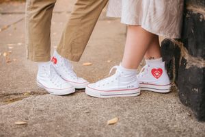 Detail shot of two pairs of white Converse sneakers with red heart designs standing side by side.