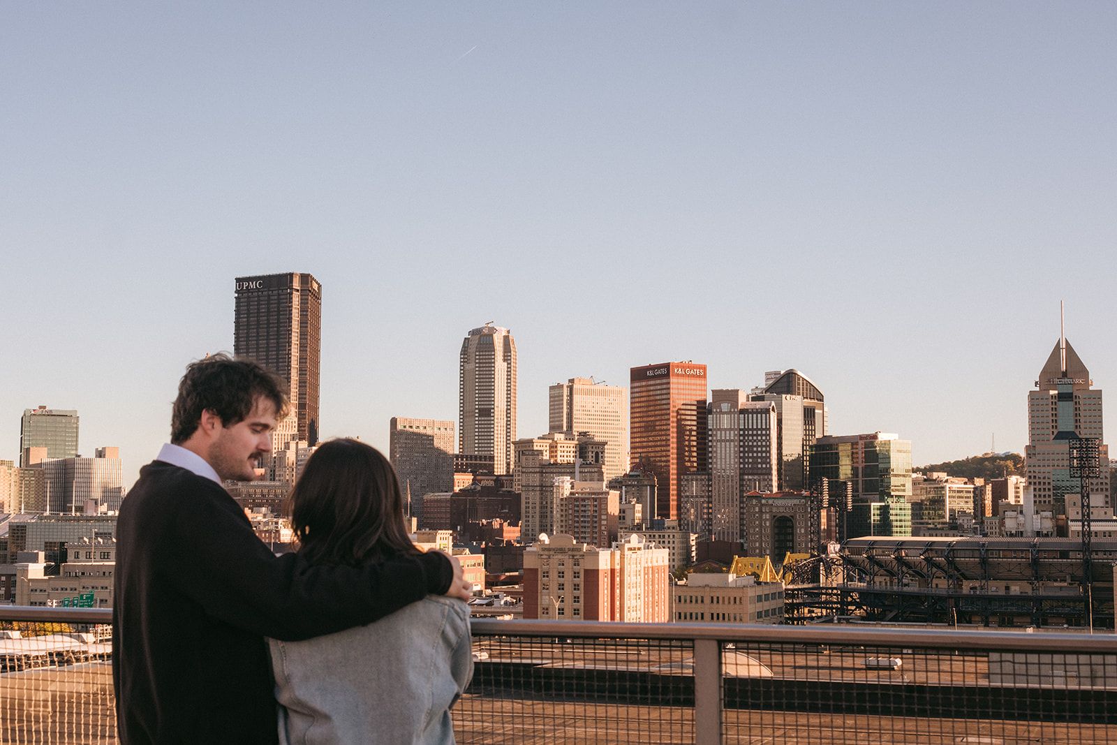 A couple shares an intimate moment overlooking the downtown Houston skyline at sunset.