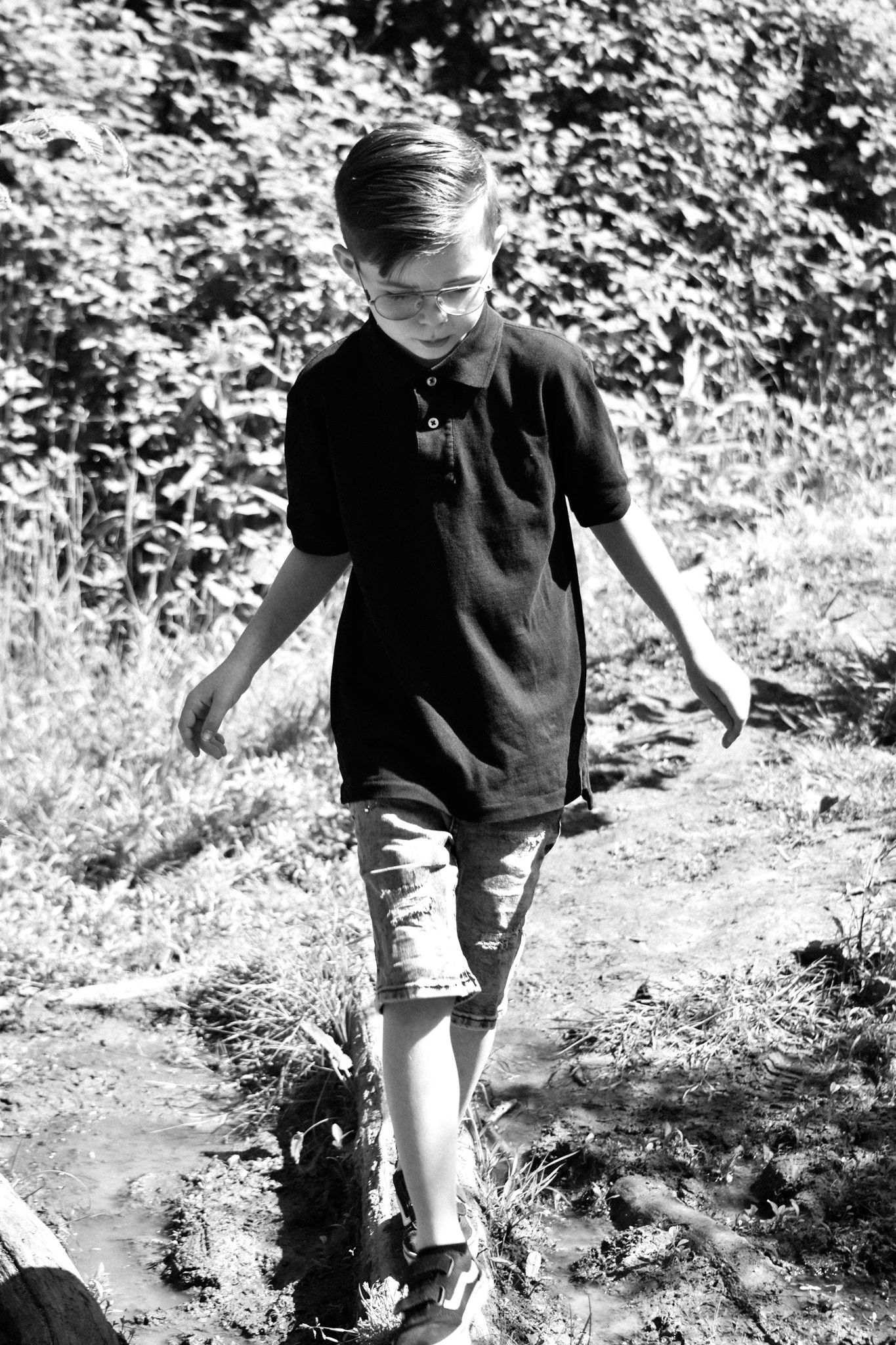Black and white photo of young person walking on outdoor trail.