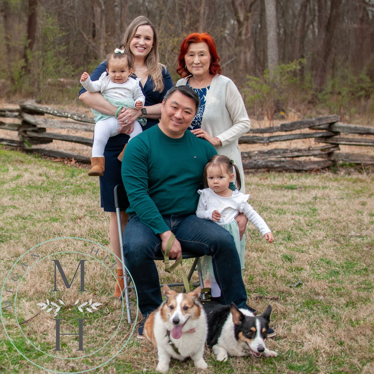 Family poses together outdoors on a grassy field with their two Corgi dogs at Ellanor C Lawrence park.