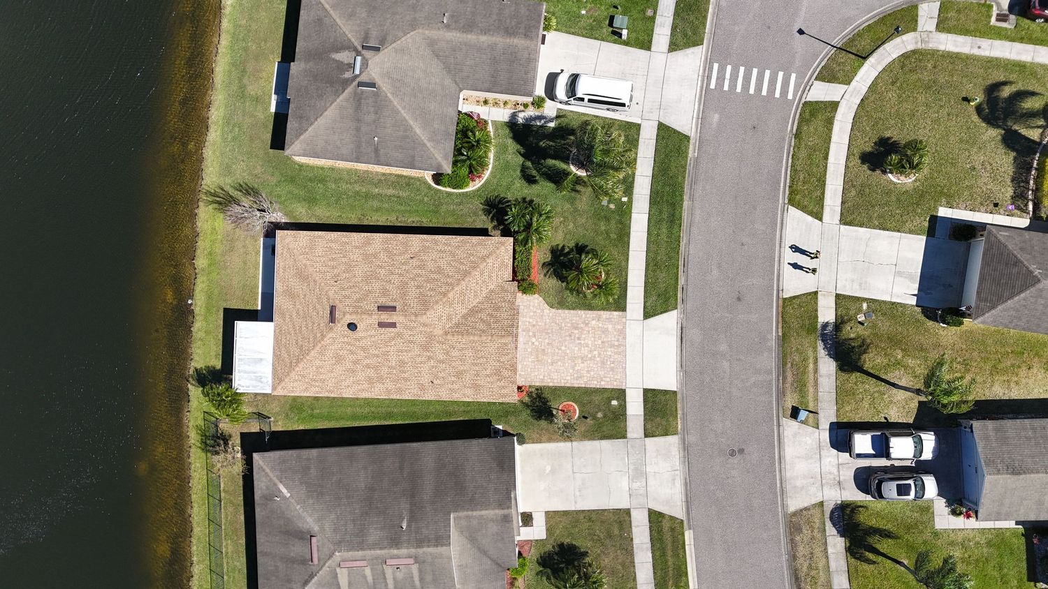 Birds-eye view of suburban cul-de-sac with tan roofed houses and landscaped yards.