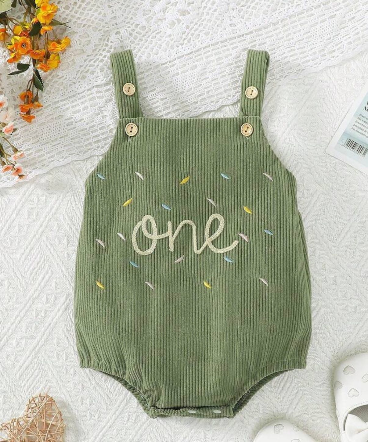 Sage green ribbed baby romper with 'one' text and confetti pattern design.