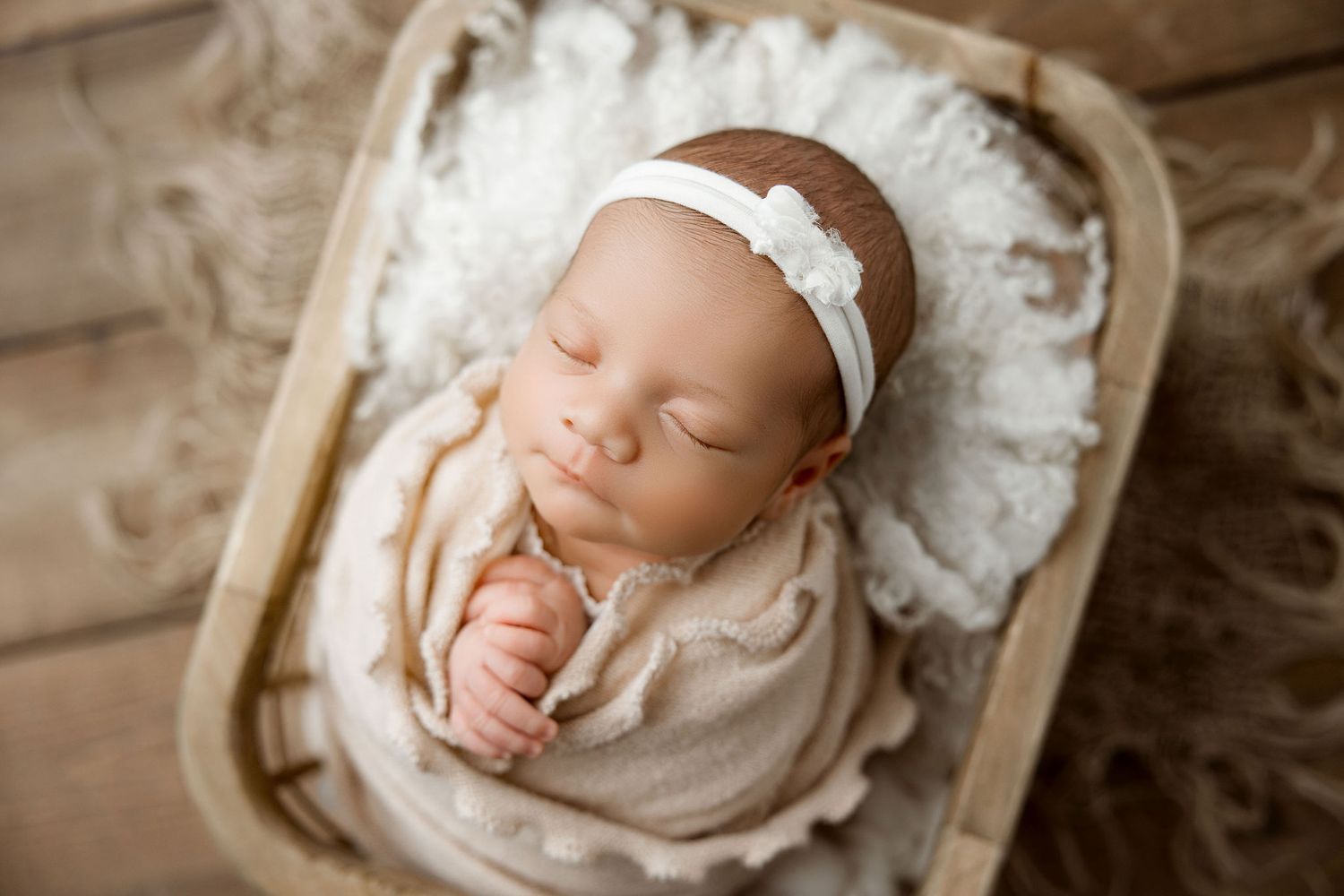 Sweet baby girl wrapped and posed in a wooden basket