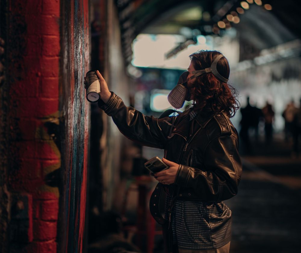 Female artist creating graffiti artwork in Leake Street Graffiti Tunnel, London captured by Shayla Bloom Photography