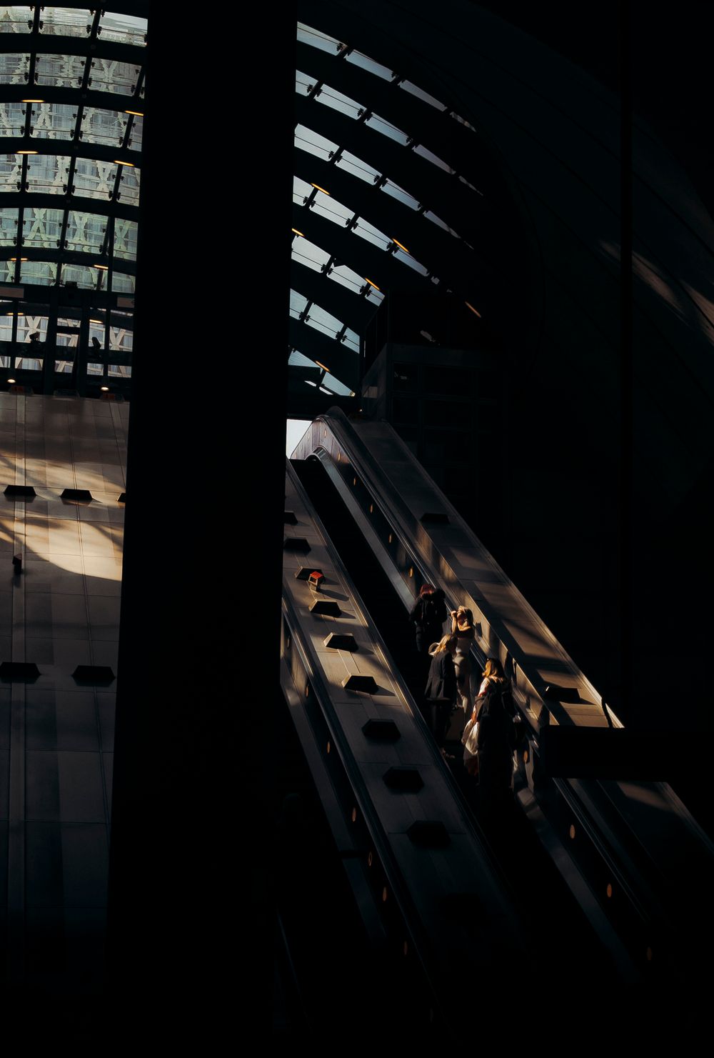 People on an escalator in the London Underground illuminated by light, captured by Shayla Bloom Photography