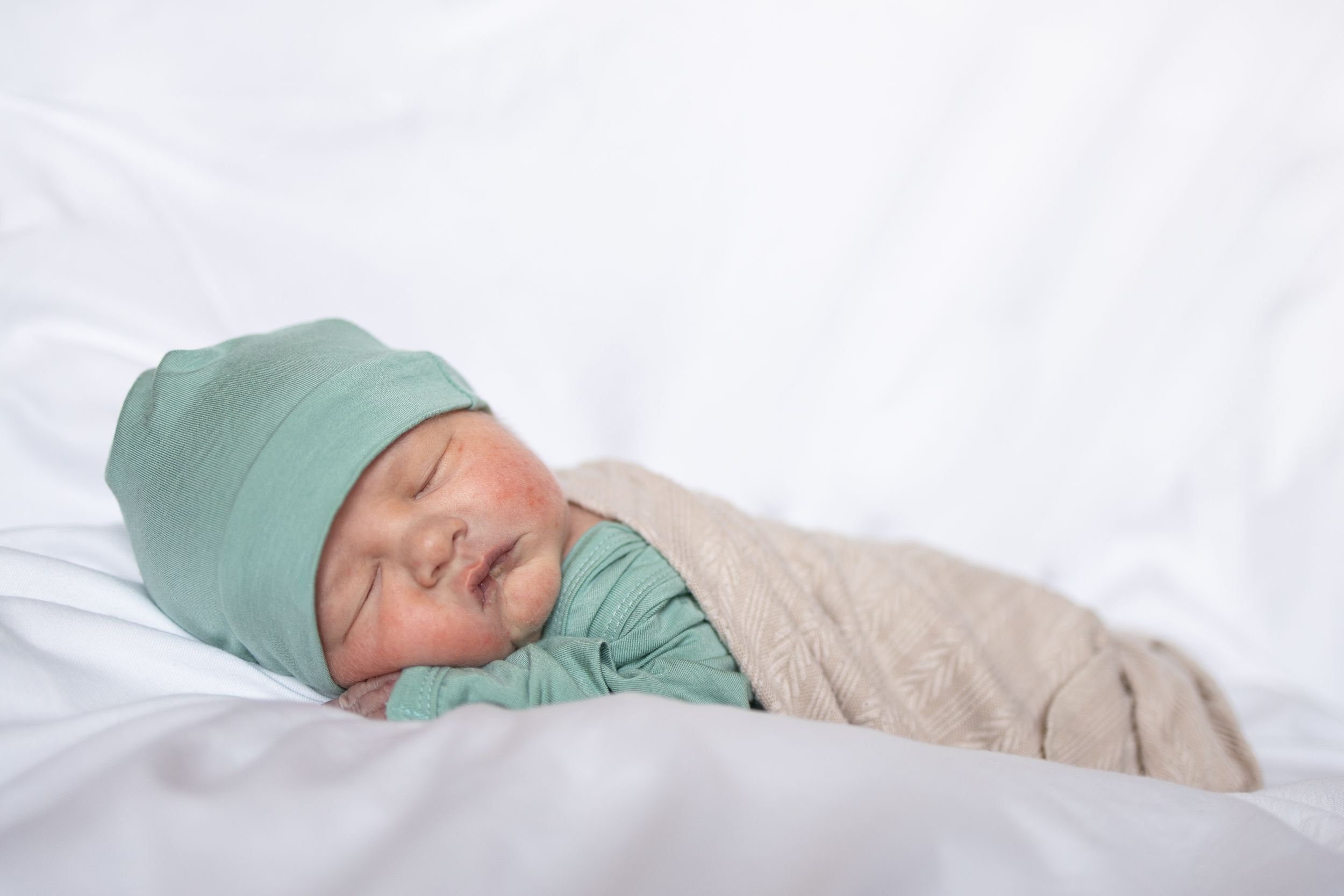 Newborn baby sleeping on his tummy with a white backdrop