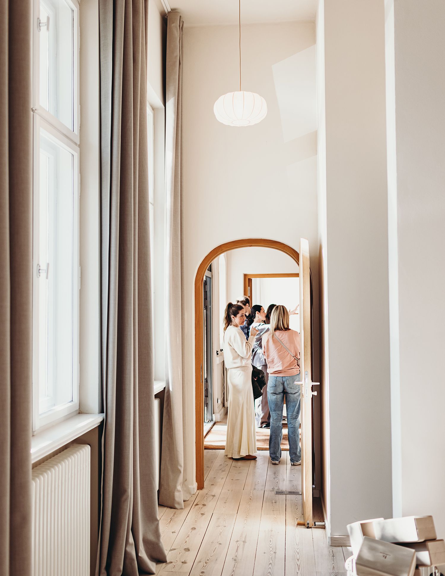 Interior hallway with arched mirrors and natural light streaming through tall windows.
