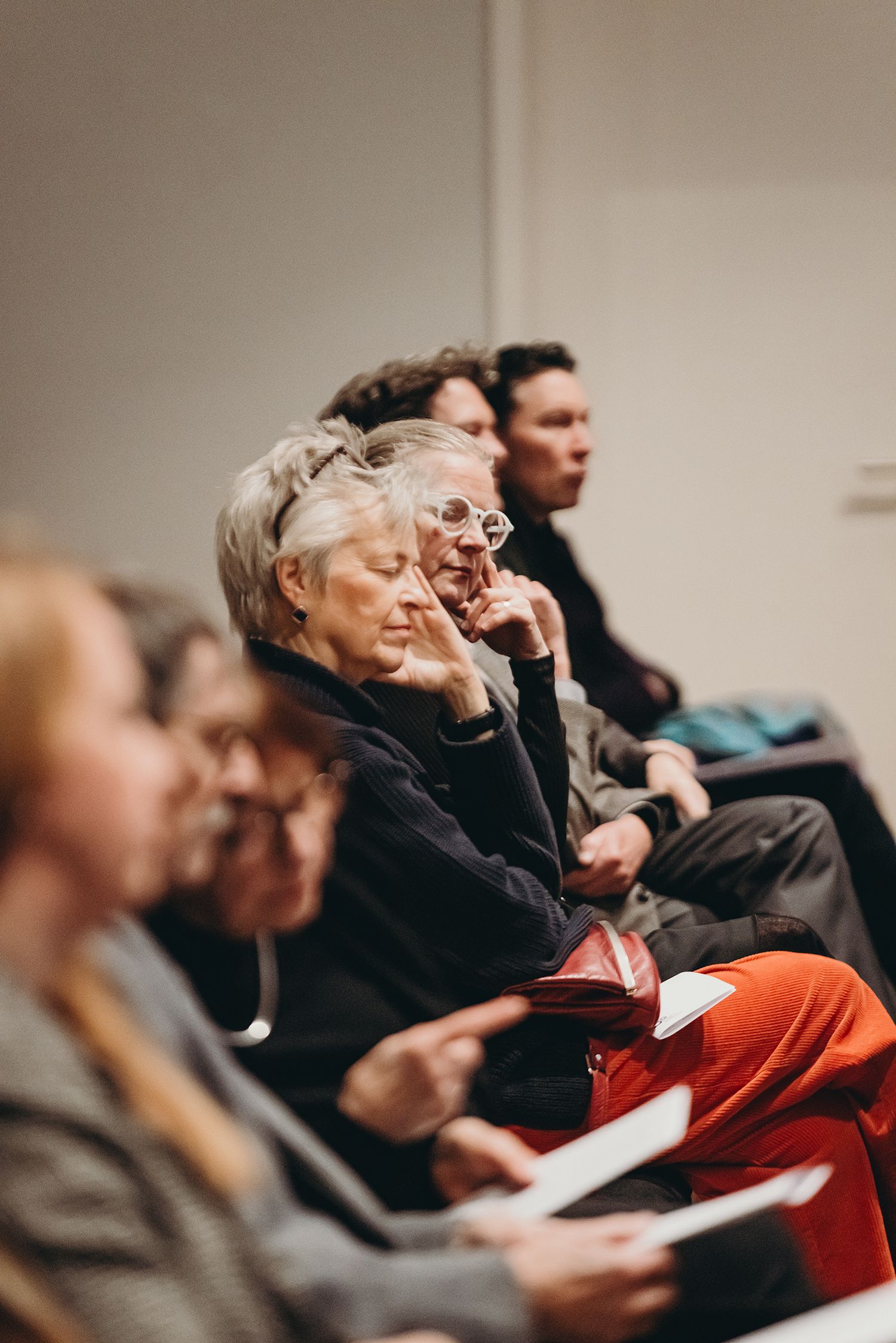Audience members seated in chairs watching intently during a presentation.
