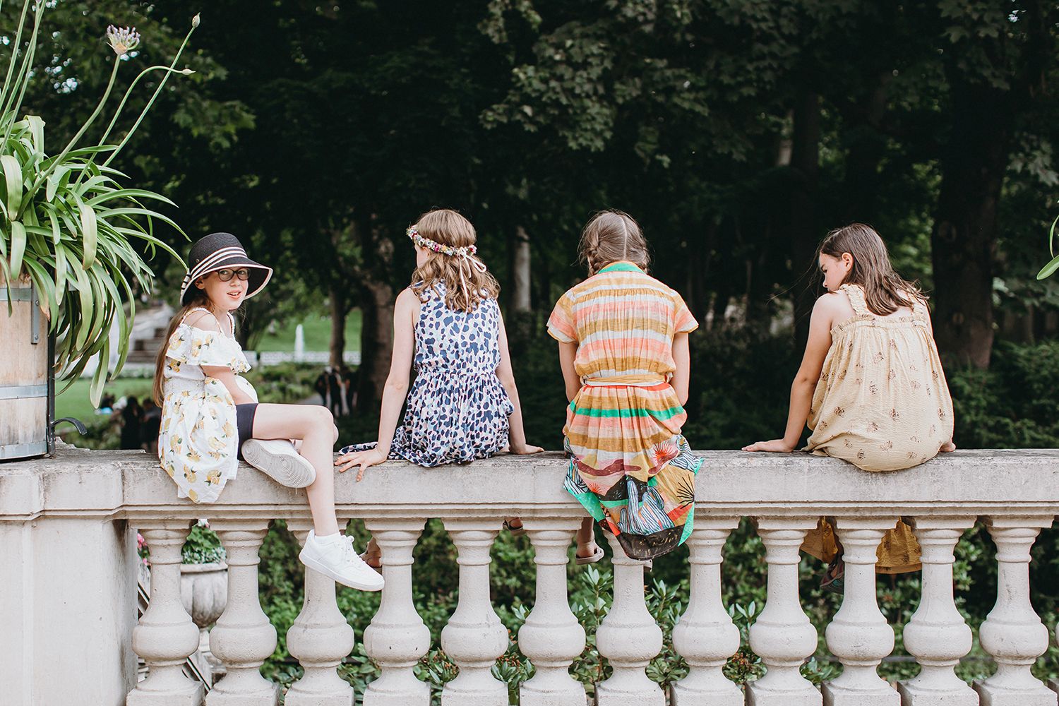 Wedding guests relaxing on an ornate white stone balustrade during the reception.
