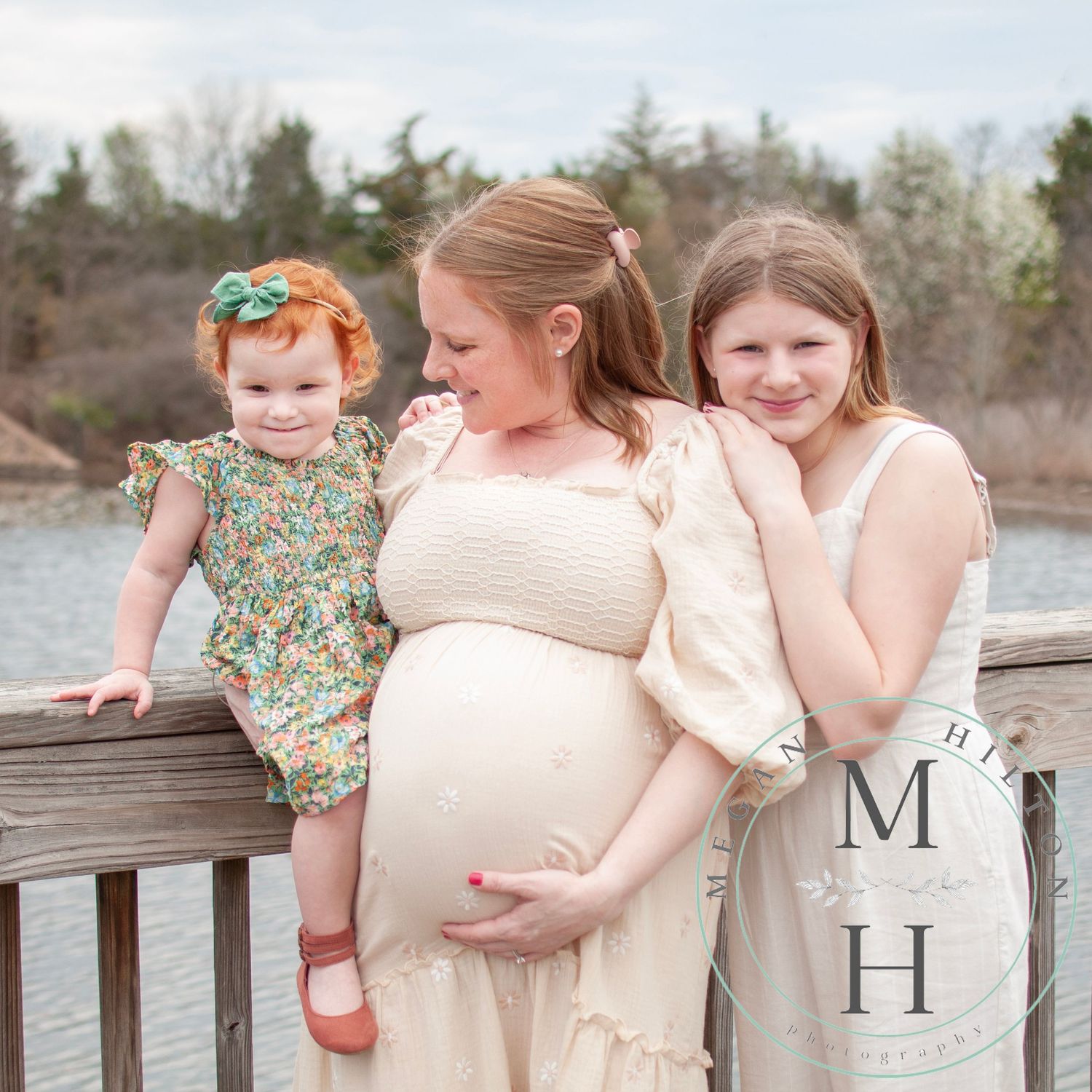 Photo captured on a wooden dock by the water with three people together sharing smiles and joy.