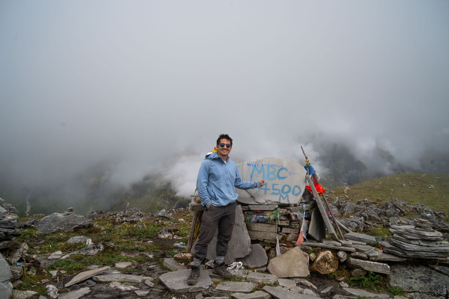Rocky mountain terrain with hikers traversing a rugged trail surrounded by misty peaks.