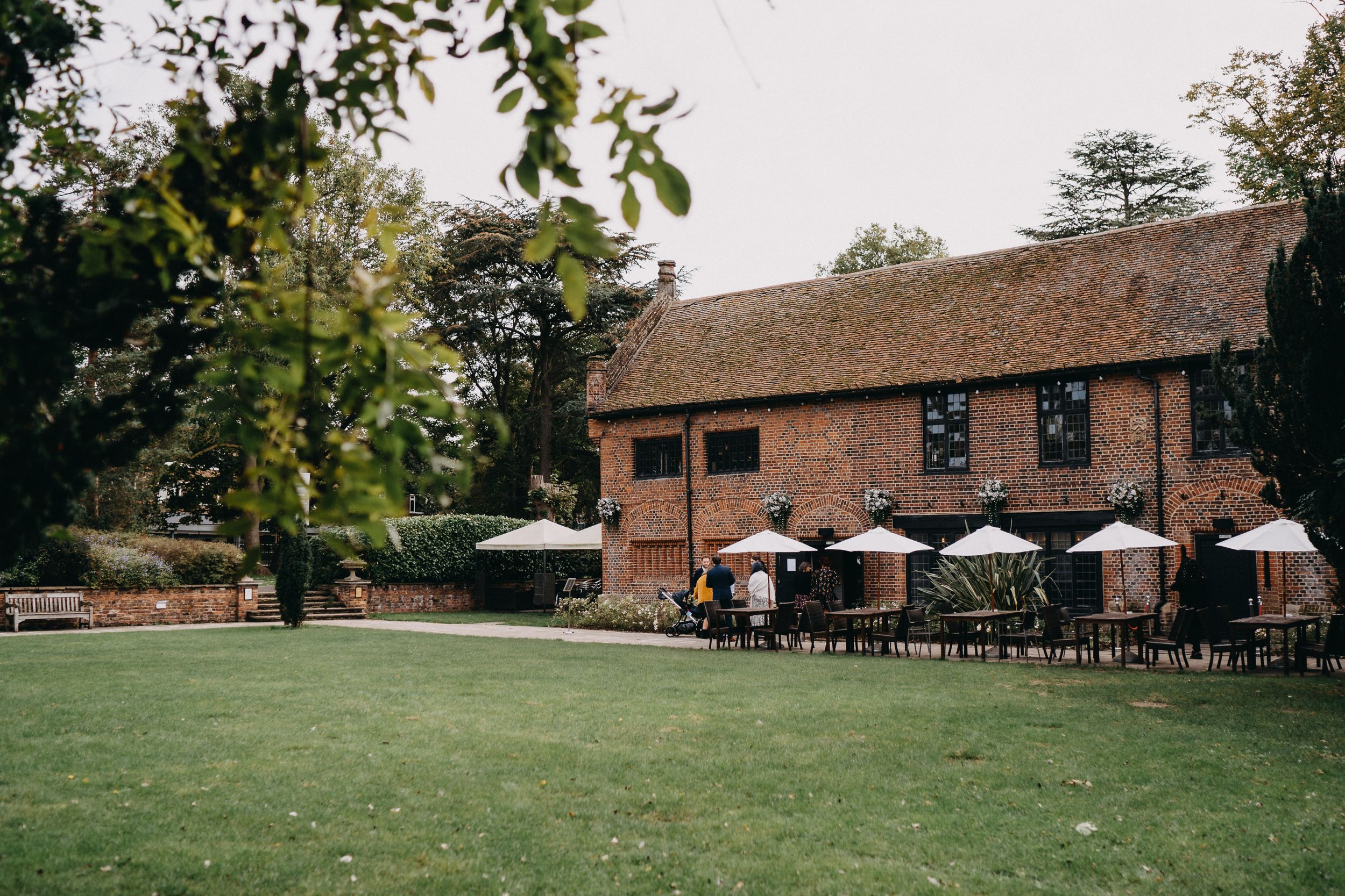 Rustic Tudor Barn Eltham with outdoor seating area featuring white umbrellas on a grassy lawn.