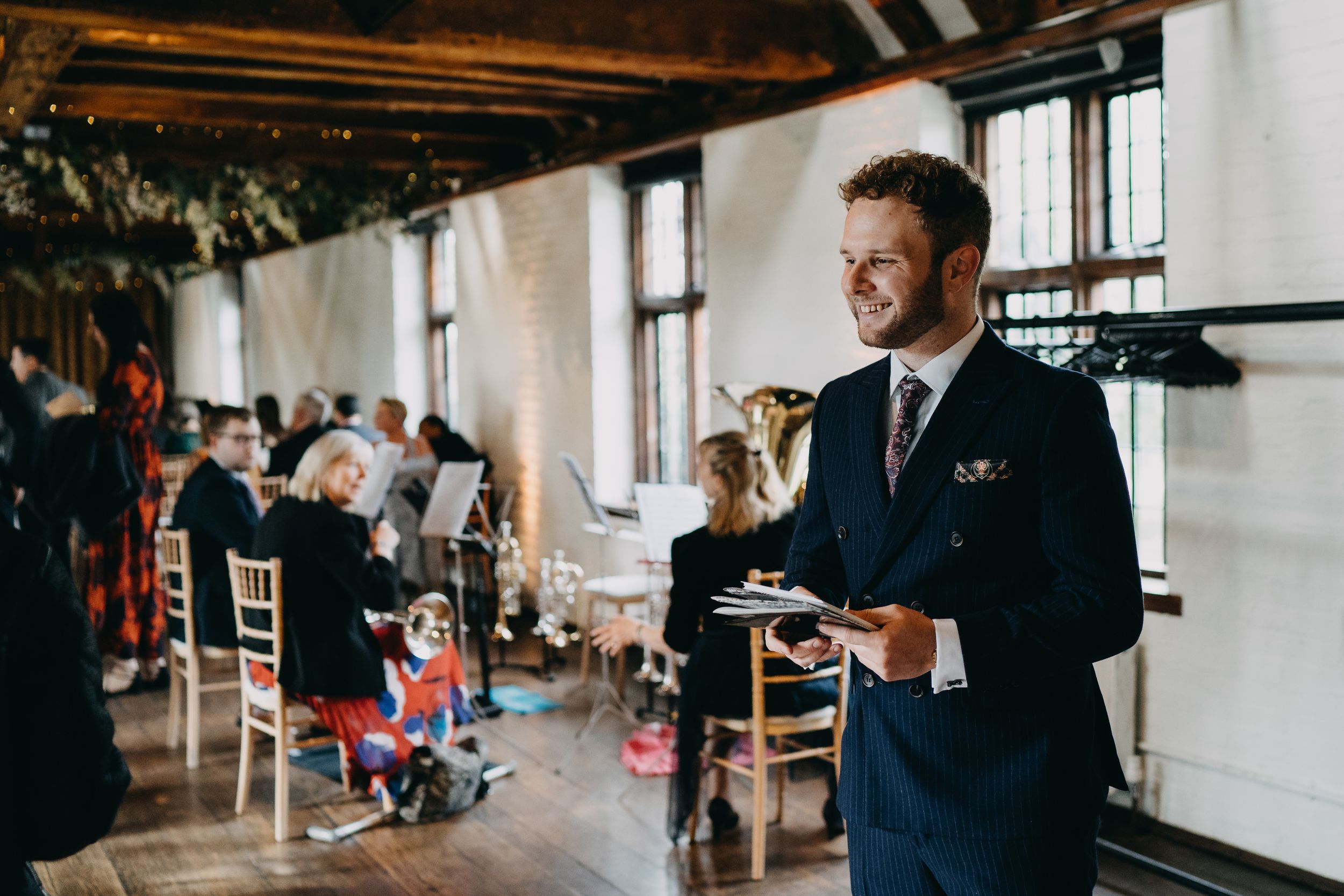 Wedding celebration in rustic indoor venue with wooden beams and bright windows.