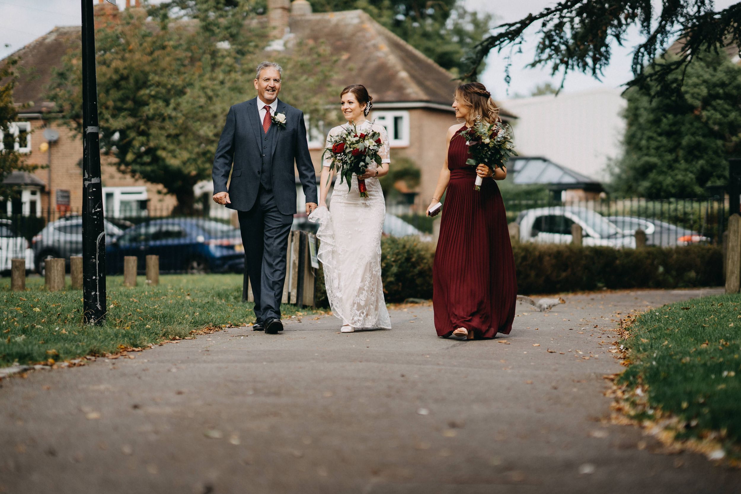 Formal procession walking down path outside traditional brick building.