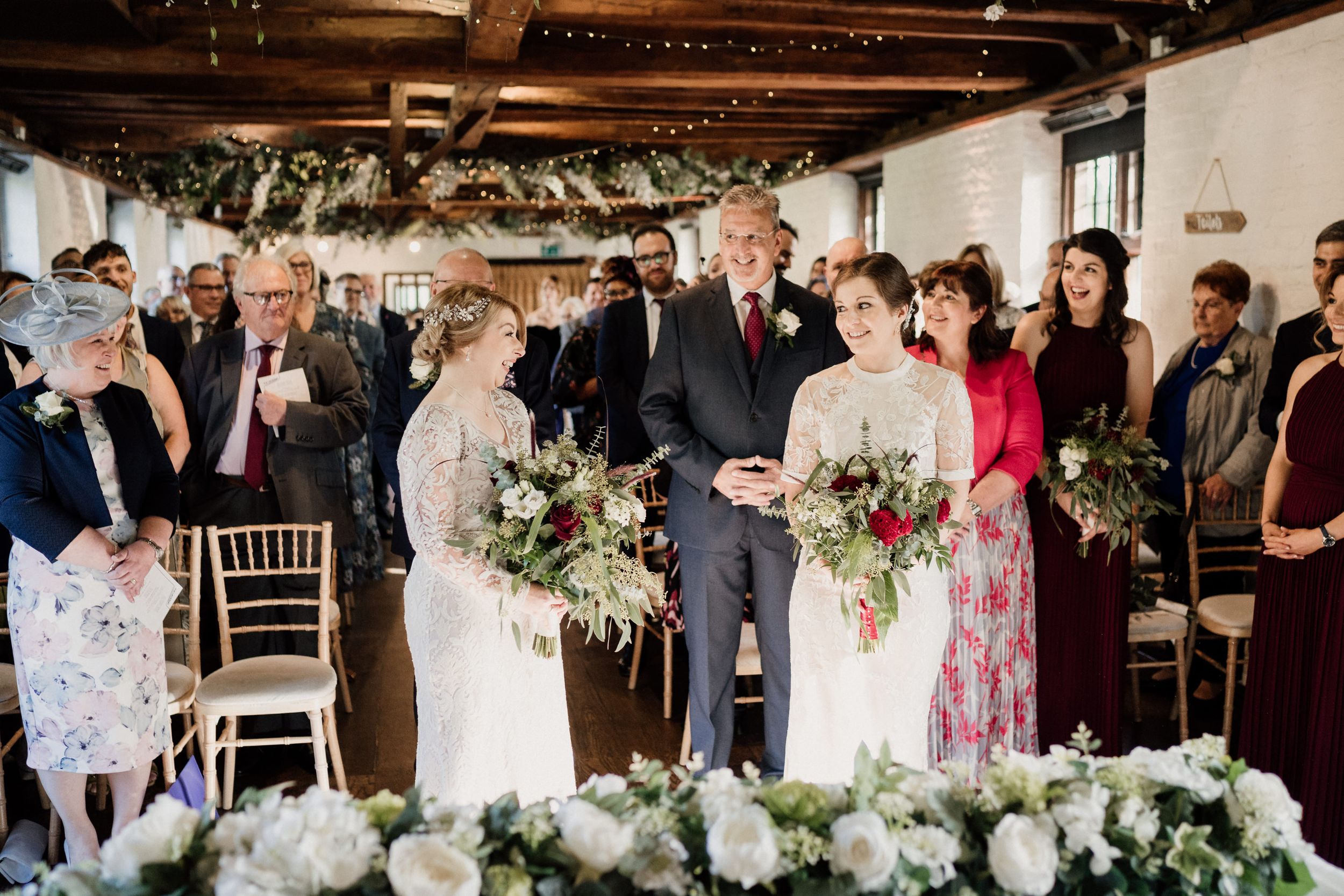 Wedding celebration in rustic venue with floral decorations and wooden ceiling beams.