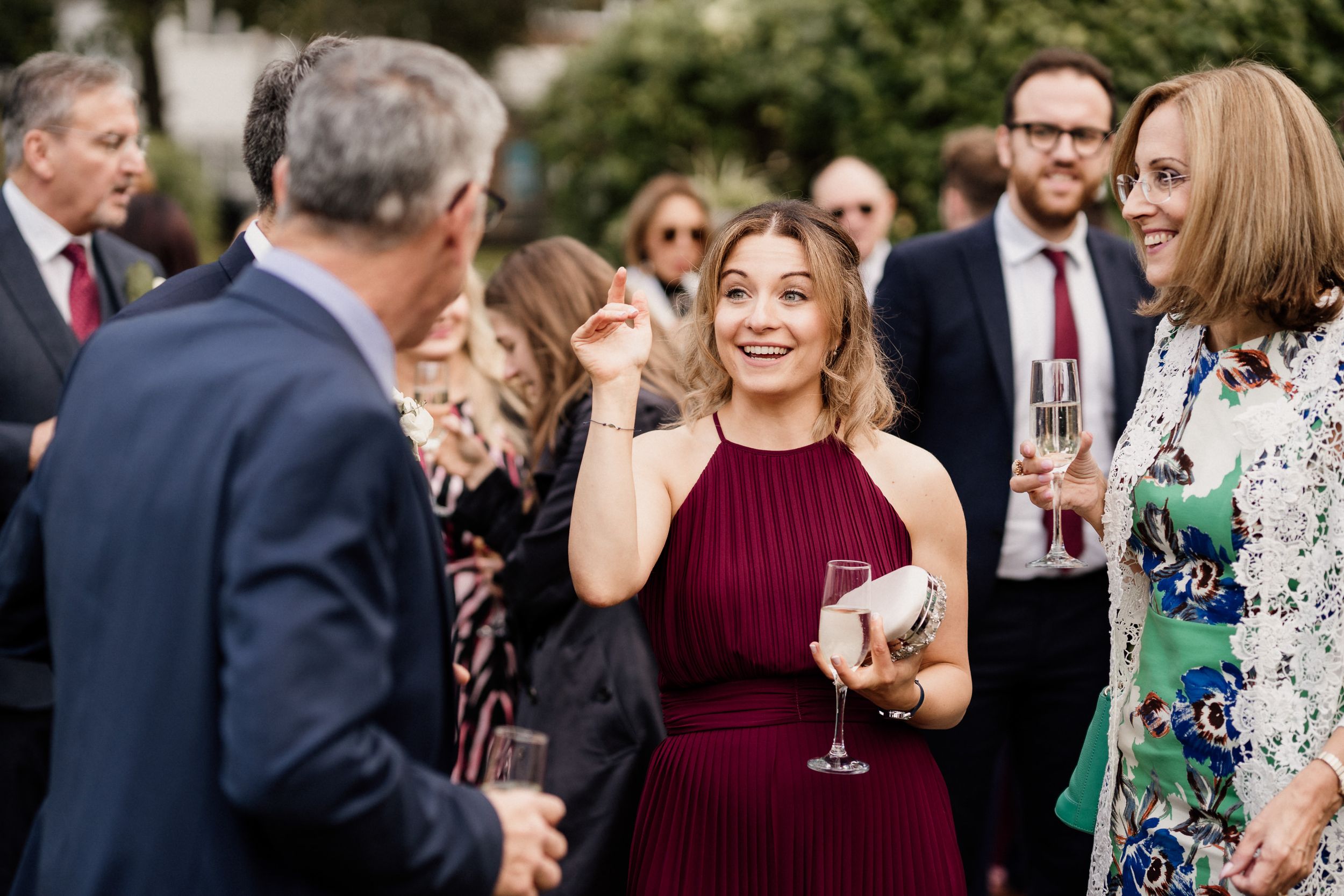 Wedding guests enjoying drinks and conversation during outdoor reception.