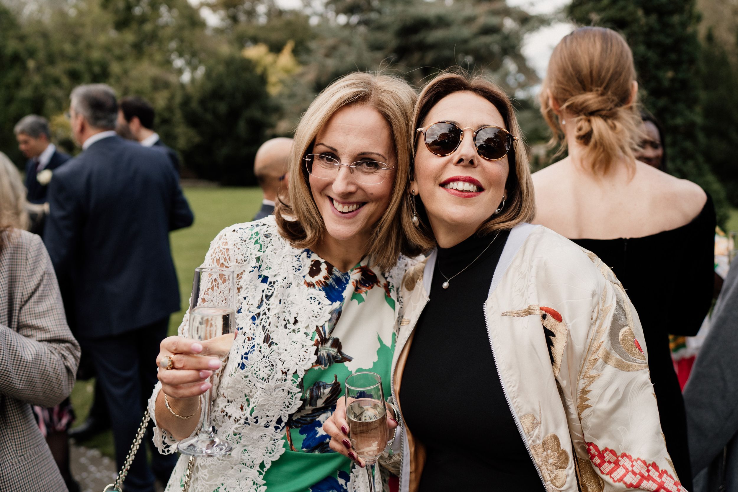 Wedding guests pose with champagne glasses at outdoor reception.