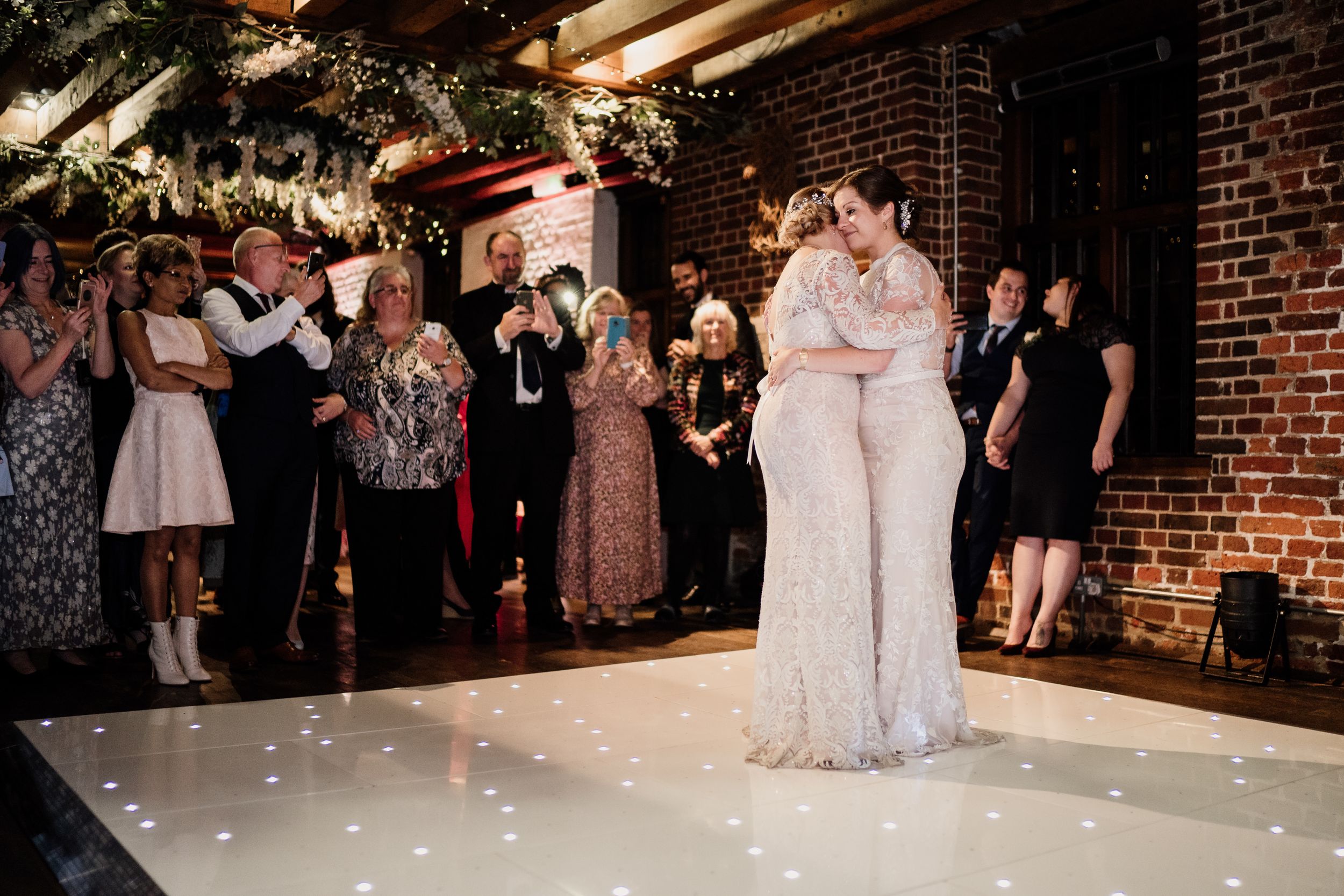 Couple sharing their first dance on illuminated white dance floor at wedding reception.