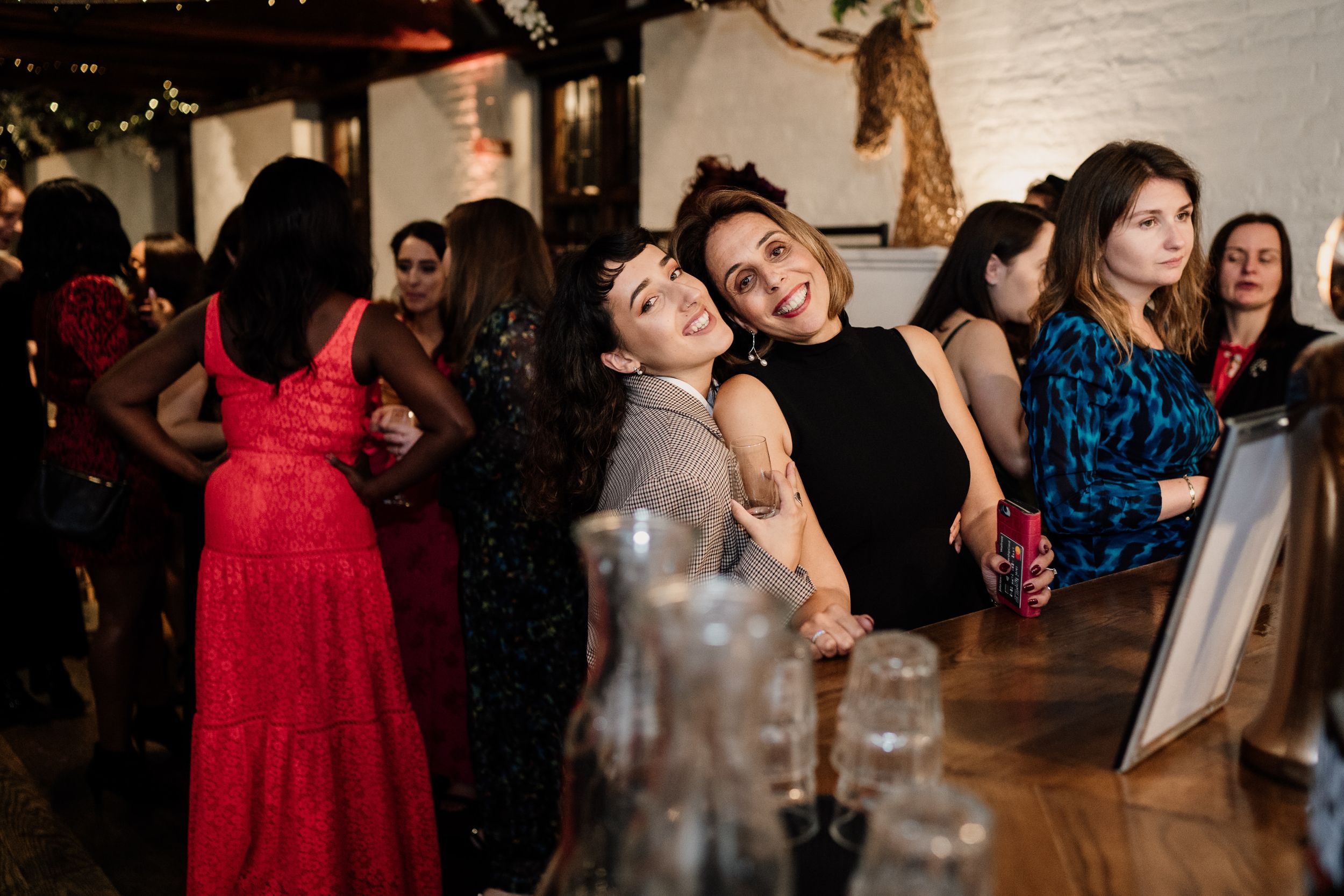 Friends enjoying drinks and laughter at a festive party bar.