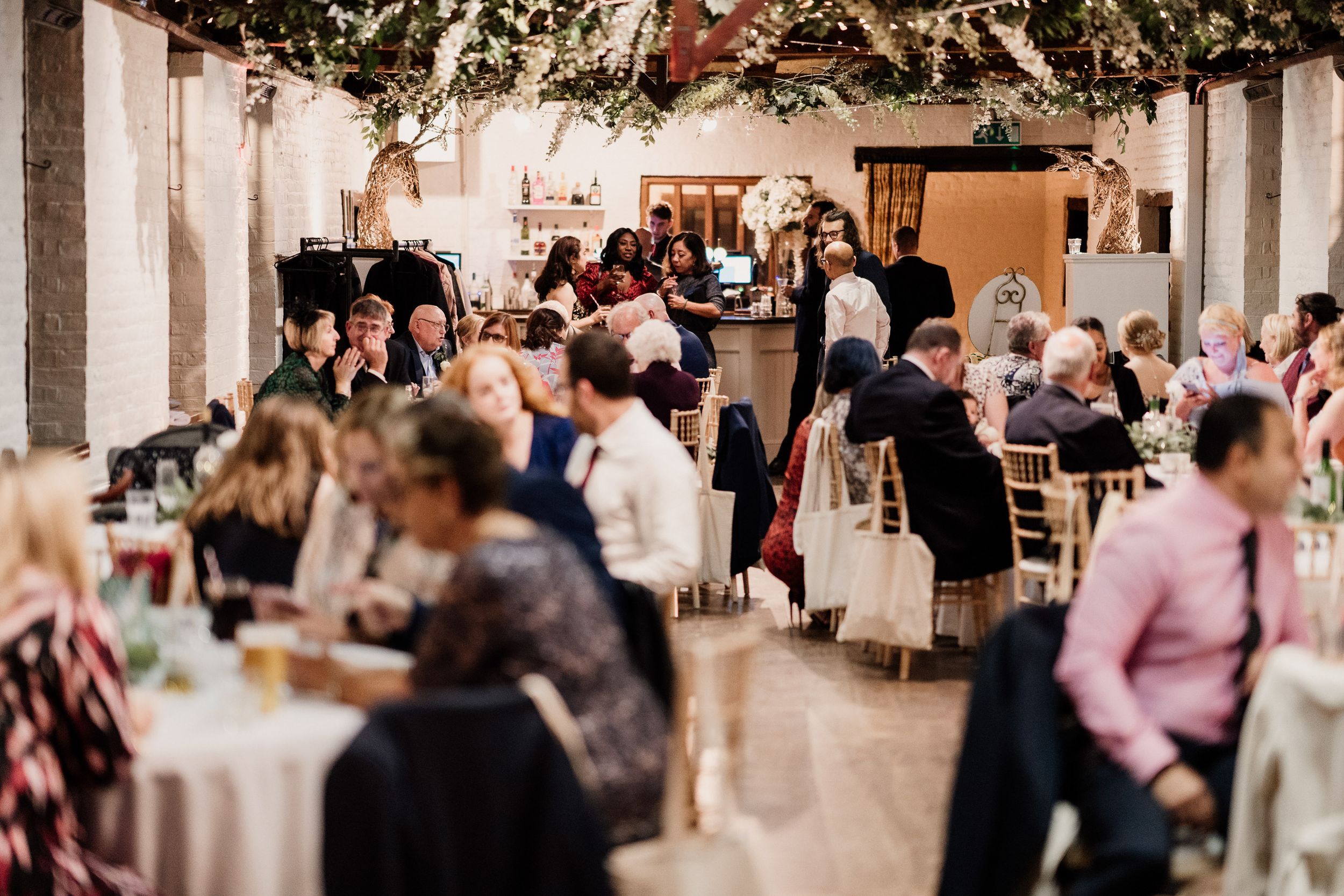 Wedding reception at Tudor Barn with elegant white decor and guests mingling.