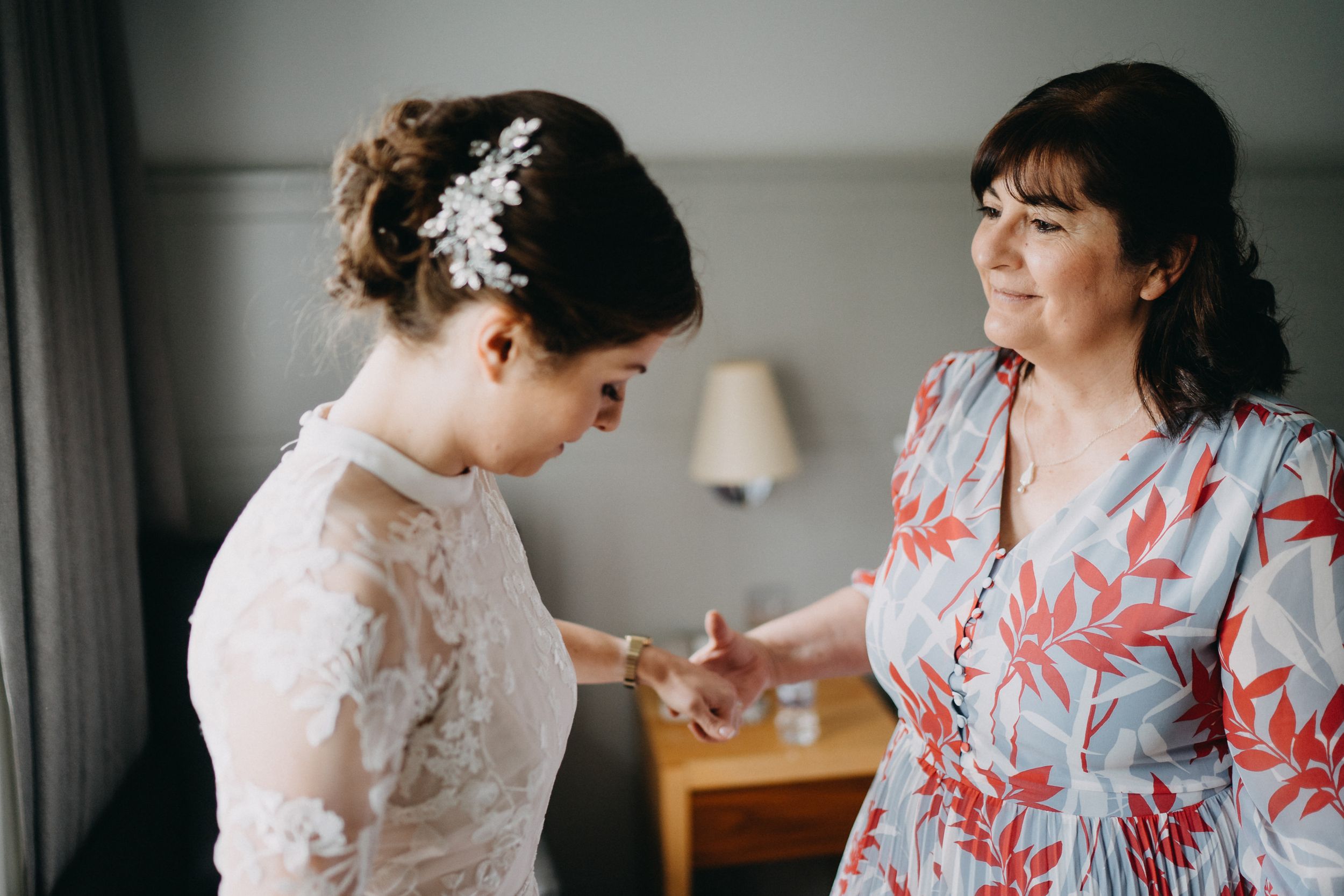 Final wedding preparations with two people in a sunlit room.