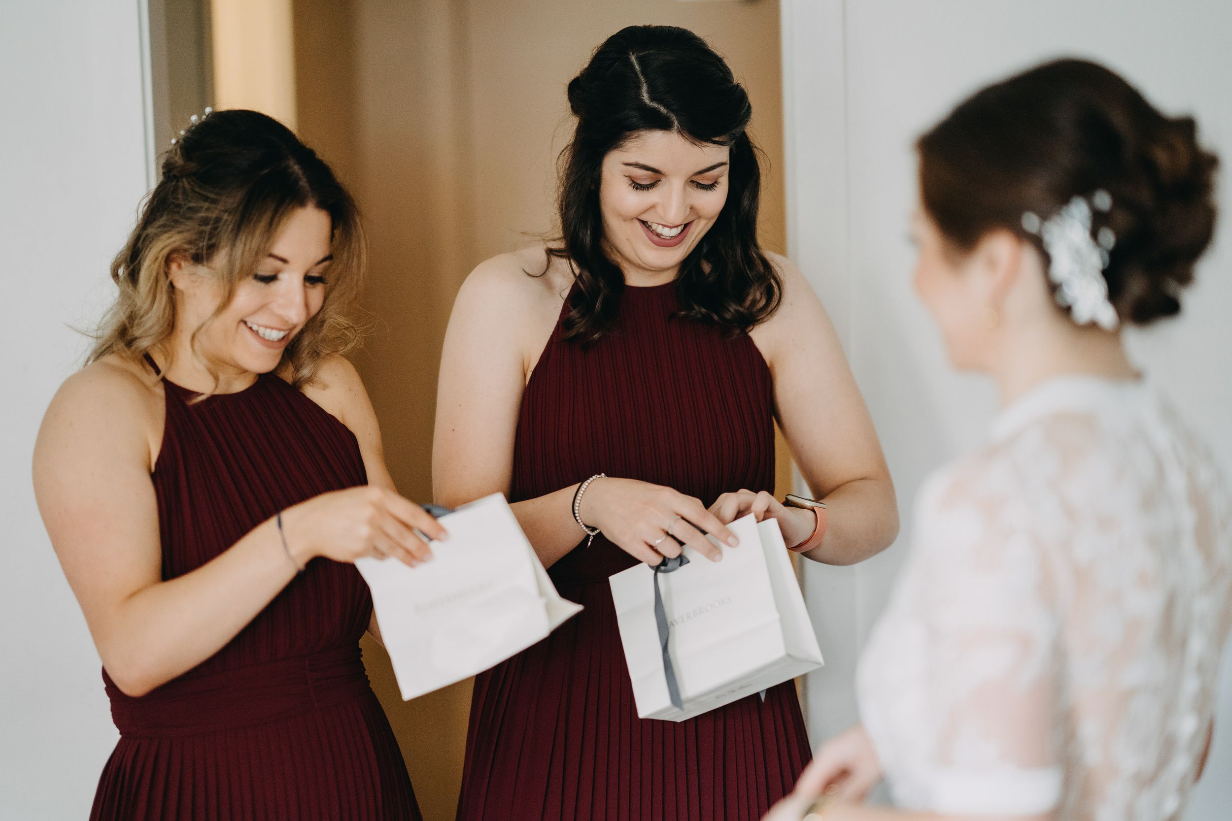 Bridesmaids in burgundy dresses helping with wedding preparations.