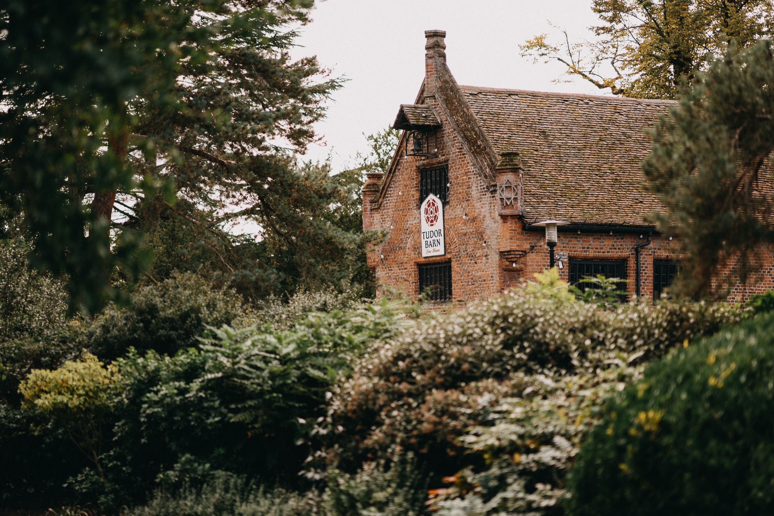 Tudor Barn Eltham A rustic cottage with Tudor-style architecture surrounded by lush gardens.